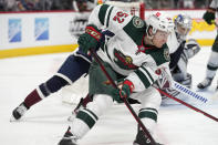 Minnesota Wild center Connor Dewar, front, wraps around the net with the puck to put a shot against Colorado Avalanche goaltender Darcy Kuemper in the second period of an NHL hockey game Monday, Jan. 17, 2022, in Denver. (AP Photo/David Zalubowski)