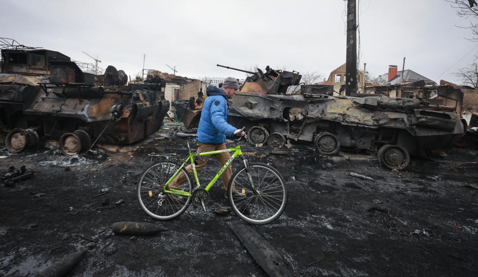 A man walks past the remains of Russian military vehicles in Bucha, close to the capital Kyiv, Ukraine, Tuesday, March 1, 2022. Russia on Tuesday stepped up shelling of Kharkiv, Ukraine's second-largest city, pounding civilian targets there. Casualties mounted and reports emerged that more than 70 Ukrainian soldiers were killed after Russian artillery recently hit a military base in Okhtyrka, a city between Kharkiv and Kyiv, the capital. (AP Photo/Serhii Nuzhnenko)