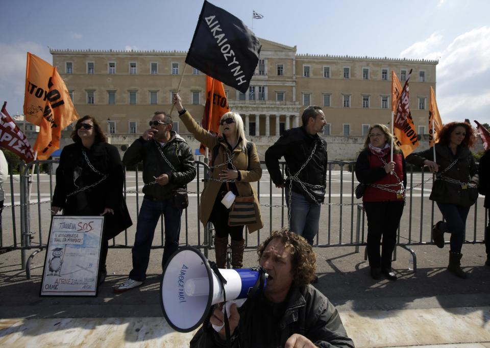 Protesting teachers chained themselves to railings in front of parliament during a rally in Athens on Wednesday, March 12, 2014. A 24-hour strike by civil servants disrupted public services in Greece Wednesday as the country’s government struggled to hammer out a deal on further austerity measures with international creditors. Thousands of protesters attended rallies in Athens and other Greek cities, while civil servants have penciled in another 48-hour strike on March 19-20. (AP Photo/Thanassis Stavrakis)