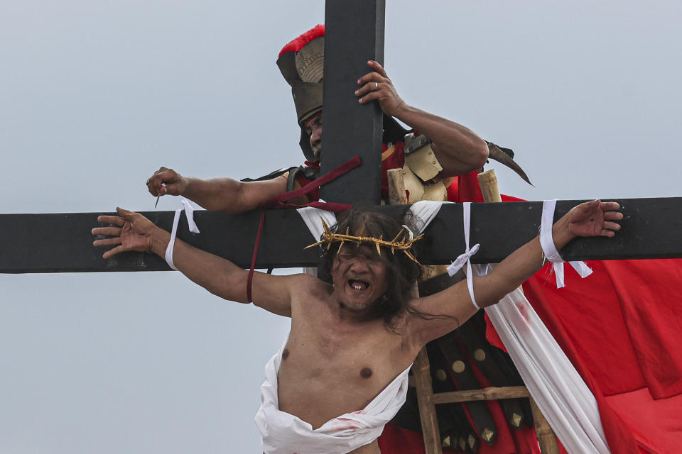 Ruben Enaje grimaces as a nail was removed from one of his hands during the reenactment of Jesus Christ's sufferings as part of Good Friday rituals in San Pedro Cutud, north of Manila, Philippines, Friday, March 29, 2024. The Filipino villager was nailed to a wooden cross for the 35th time to reenact Jesus Christ’s suffering in a brutal Good Friday tradition he said he would devote to pray for peace in Ukraine, Gaza and the disputed South China Sea. (AP Photo/Gerard V. Carreon)