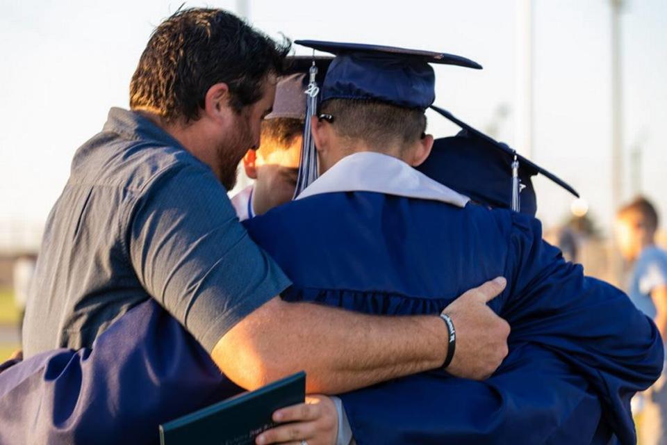 A group of Stone Ridge Christian seniors embrace with Andrew Kahler, left, at the high school’s graduation ceremony on Thursday, May 21, 2020 at Castle Field.