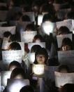 Students hold papers with candles as they pray for the safe return of their friends aboard the sunken ferry Sewol at Danwon High School in Ansan, south of Seoul, South Korea, Friday, April 18, 2014. Rescuers scrambled to find hundreds of ferry passengers still missing Friday and feared dead in the waters off the country's southern coast, as fresh questions emerged about whether quicker action by the captain of the doomed ship could have saved lives. (AP Photo/Yonhap) KOREA OUT