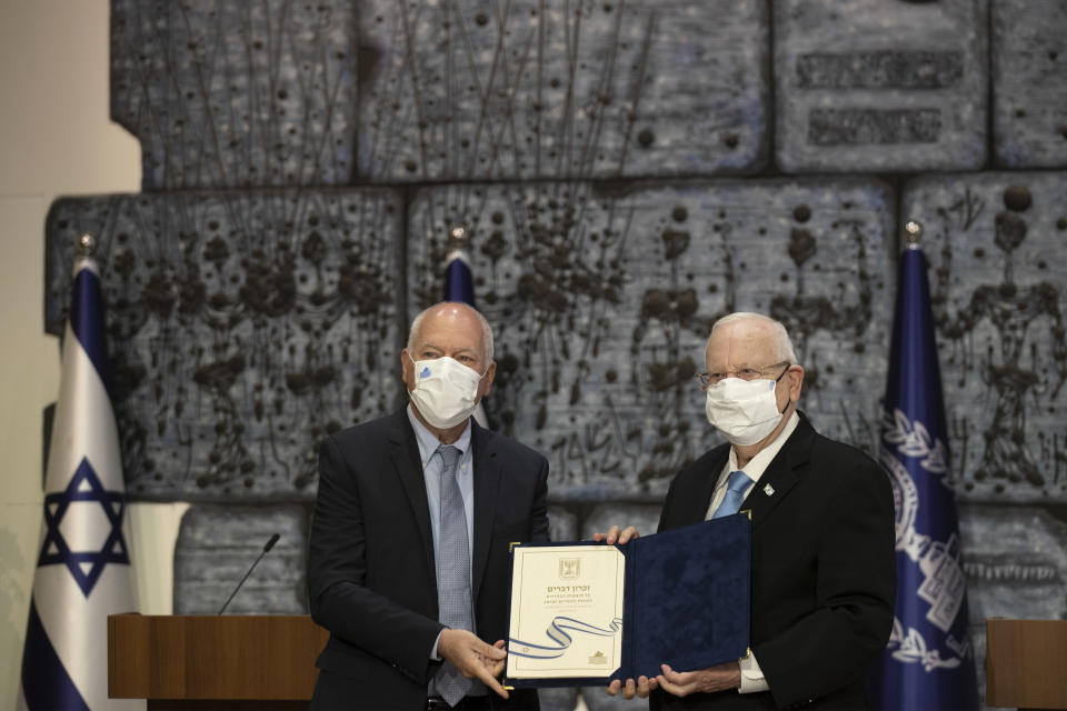 Chairman of Israel's Central Elections Committee Judge Uzi Fogelman, left, poses with Israeli President Reuvin Rivlin with official election results in Jerusalem, Wednesday, March 31, 2021. Israeli election officials Wednesday handed the results of last week's vote to President Reuven Rivlin, nudging forward the country' elusive efforts to break political deadlock, form a government and avoid an unprecedented fifth consecutive round of balloting. (AP Photo/Maya Alleruzzo)