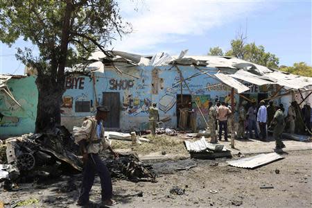 A Somali policeman walks at the scene of a suicide car bomb attack next to a tea shop in the suburbs of capital Mogadishu February 27, 2014. Islamist group al Shabaab claimed responsibility for a car bombing on Thursday that police said killed at least 10 people in the Somali capital Mogadishu and threatened more attacks. REUTERS/Feisal Omar (SOMALIA - Tags: CIVIL UNREST POLITICS)