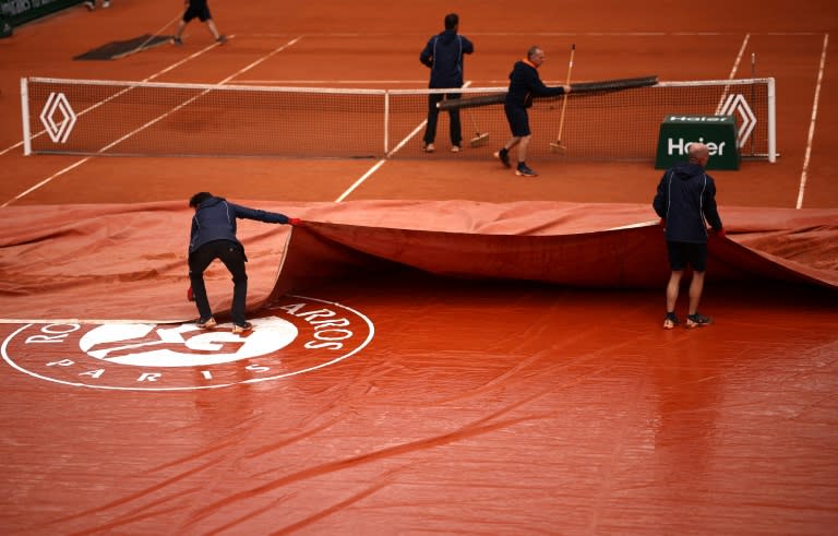 Des officiels retirent la bâche sur le court Simonne-Mathieu à Roland-Garros, le 30 mai 2024 (Anne-Christine POUJOULAT)