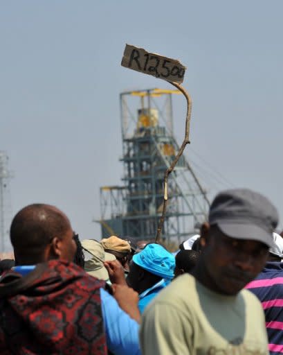 A miner holds up a sign reading 12,500 rand, the minimum baseline wage demanded by workers by the Anglo American Platinum (Amplats) mine in Rustenburg, on September 12. Two of the world's top mining giants toughened their line against striking South African workers, with one threatening to sack employees and the other warning of plant closures if stoppages continued