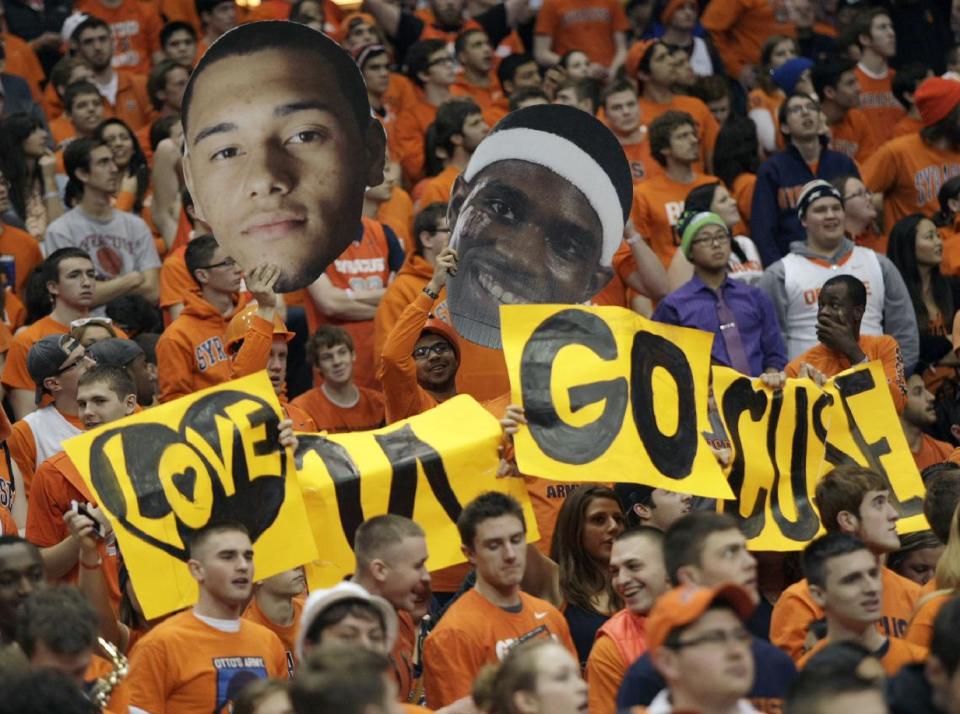 Syracuse fans cheer while waving cutouts of Syracuse players Tyler Ennis, left, and C.J. Fair, right, in the second half of an NCAA college basketball game against Pittsburgh in Syracuse, N.Y., Saturday, Jan. 18, 2014. Syracuse won 59-54. (AP Photo/Nick Lisi)