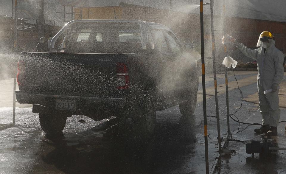 Un trabajador de la ciudad dirige un automóvil a través de un arco desinfectante el miércoles 27 de mayo de 2020 en un intento por contener la propagación del coronavirus, antes de ingresar a la comunidad de Mallasa en las afueras de La Paz, Bolivia. (AP Foto/Juan Karita)