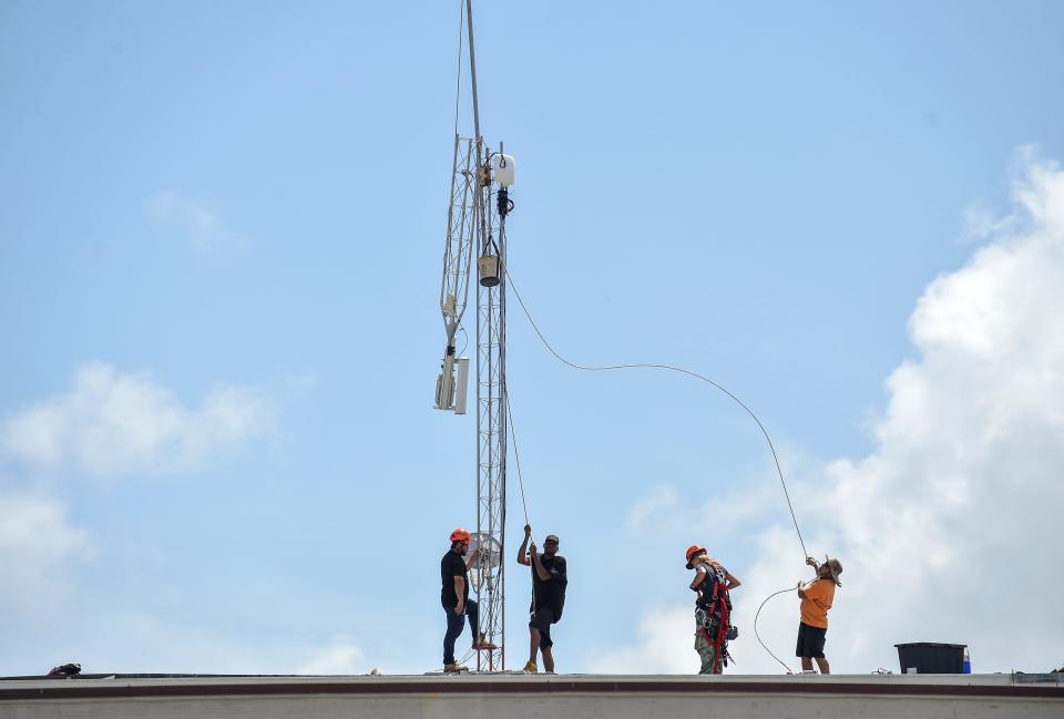 A crew from internet service provider Florida Broadband works to remove an access tower from the roof of the Theater Plaza building on 14th Avenue in Vero Beach, Fla., on Saturday, Aug. 31, 2019, in preparation for the possible arrival of Hurricane Dorian.