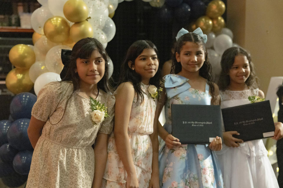 Sophia Prado, left, takes a picture with her classmates after a graduation ceremony at Trevor Day School, Friday, June 21, 2024, in New York. Thousands of migrant families in New York City are facing a summer of uncertainty for their school-aged children with a citywide limit of 60 days in a shelter before needing to reapply or find their own. (AP Photo/Jeenah Moon)