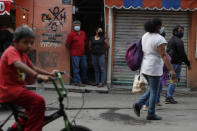 José Juan Serralde y su esposa Blanca Evangelista Villada aparecen en la puerta de entrada a su casa, en San Gregorio Atlapulco, Xochimilco, en Ciudad de México, el miércoles 29 de julio de 2020. Los padres de Serralde, que vivían con ellos, murieron por COVID-19 en mayo, mientras que ellos y dos de sus cuatro hijas se contagiaron aunque con síntomas menores. (AP Foto/Rebecca Blackwell)