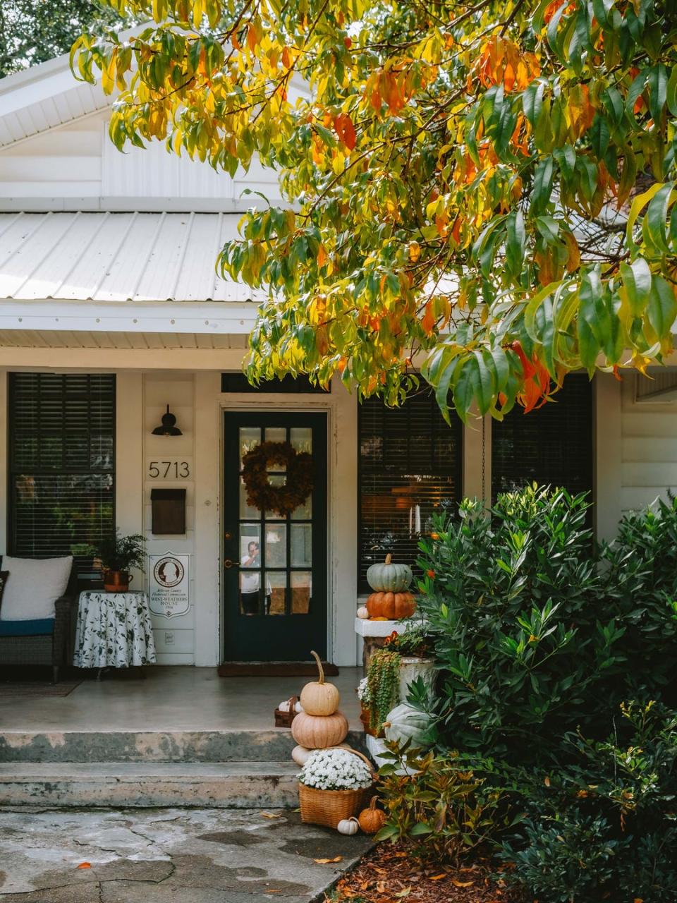 front porch decorated for falll with pumpkins and mums