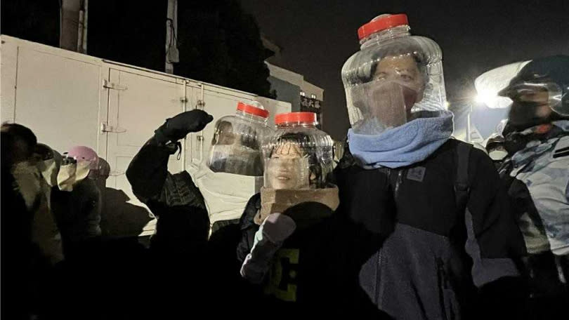 台南鹽水蜂炮遶境24日晚間登場，許多人來體驗犁蜂炮，有民眾創意發想利用塑膠水桶當頭盔。（圖／中國時報張毓翎攝）