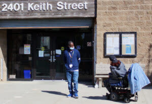 community health worker outside building talks to patient
