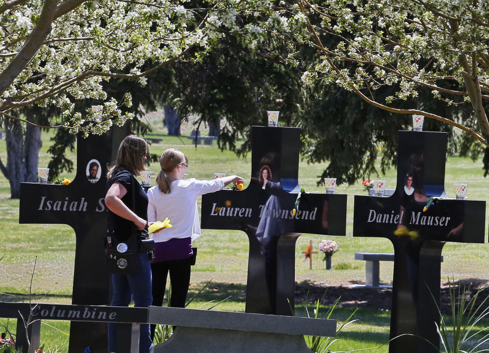 FILE - A family visits the memorial crosses dedicated to the the 13 people killed in the 1999 Columbine High School shooting attack, at Chapel Hill Memorial Gardens in Littleton, Colo., Easter Sunday, April 20, 2014. There have been dozens of shootings and other attacks in U.S. schools and colleges over the years, but until the massacre at Colorado's Columbine High School in 1999, the number of dead tended to be in the single digits. Since then, the number of shootings that included schools and killed 10 or more people has mounted .(AP Photo/Brennan Linsley, File)