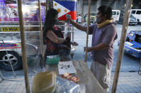 FILE - In this July 3, 2020, file photo, a passenger has her temperature checked to prevent the spread of the new coronavirus as some routes for the Traditional Jeepney buses were opened to help public transportation while the government slowly eases lockdown in metropolitan Manila, Philippines. The Philippines has seen a big recent spike in infections, raising the possibility its overcrowded capital may be placed back under a strict lockdown. (AP Photo/Aaron Favila, File)