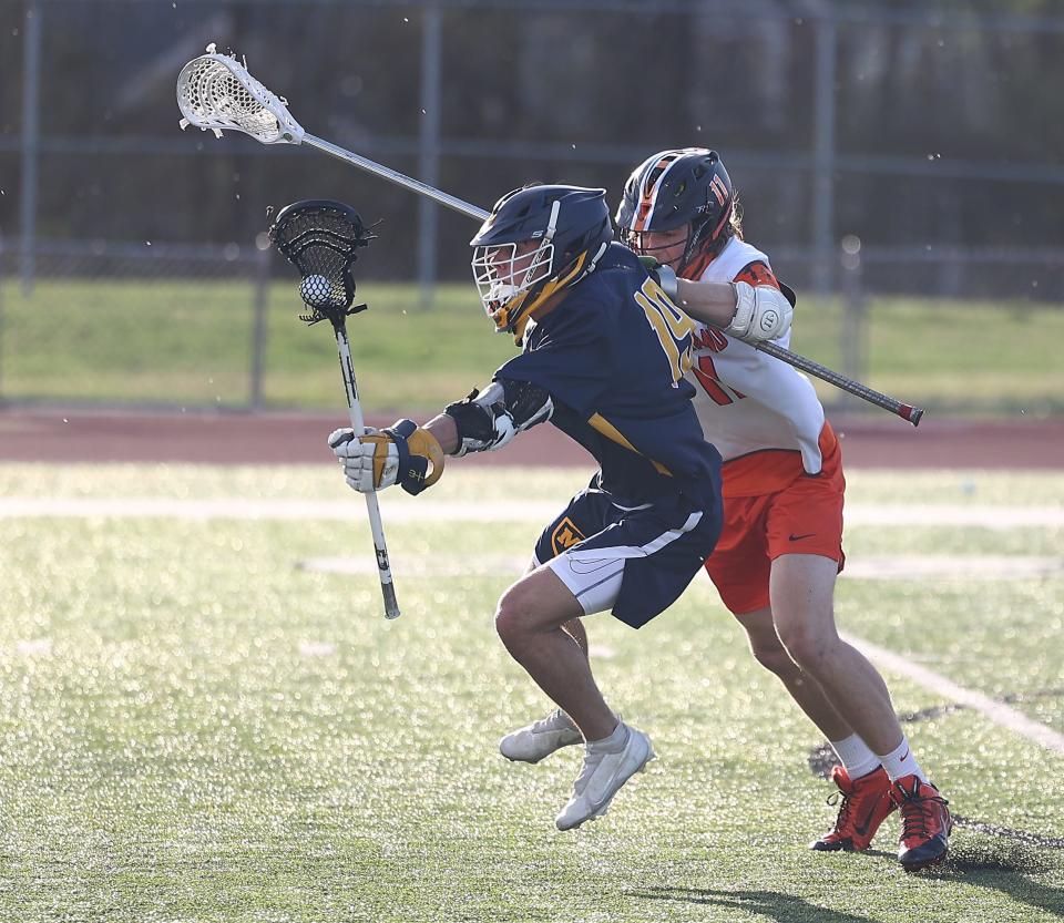 Loveland's Ethan Lund (11) pushes Moeller's Andrew Samoya during their lacrosse match, Wednesday, March 23, 2022.