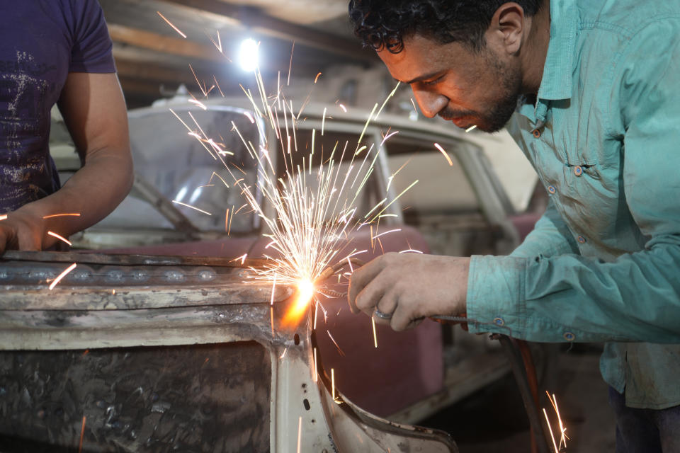 Abd Allah Ragab works on a 1966 Mercedes at a private collector's lot in El Saff city in the Giza, just outside Cairo, Egypt. Friday, April 8, 2022. Egyptian businessman and a classic car collector Mohamed Wahdan says he has accumulated more than 250 vintage, antique and classic cars over the past 20 years. (AP Photo/Amr Nabil)