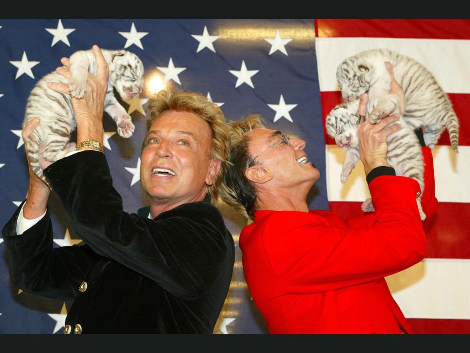 Siegfried and Roy hold royal white tiger cubs, photo