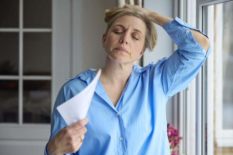 Menopausal Mature Woman Having Hot Flush At Home Cooling Herself With Letters Or DocumentsWeight loss can alleviate symptoms like hot flashes and mood swings.