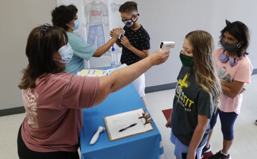 Science teachers Ann Darby, left, and Rosa Herrera check-in students at a school in Wylie, Texas.