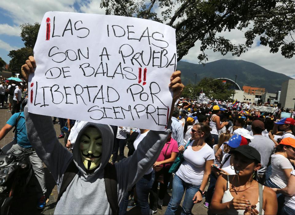 A masked opposition demonstrator holds up a poster that reads in Spanish "Ideas are bullet proof! Freedom always!" at a protest in Caracas, Venezuela, Saturday, Feb. 15, 2014. Demonstrators are protesting the Wednesday killings of two university students who were shot in different incidents after an anti-government protest demanding the release of student protesters arrested in various parts of the country. (AP Photo/Fernando Llano)