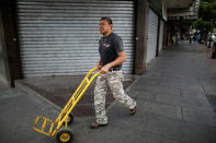 A man pushes a wheelbarrow in front of a closed store at a commercial area in Caracas, Venezuela August 21, 2018. REUTERS/Carlos Garcia Rawlins