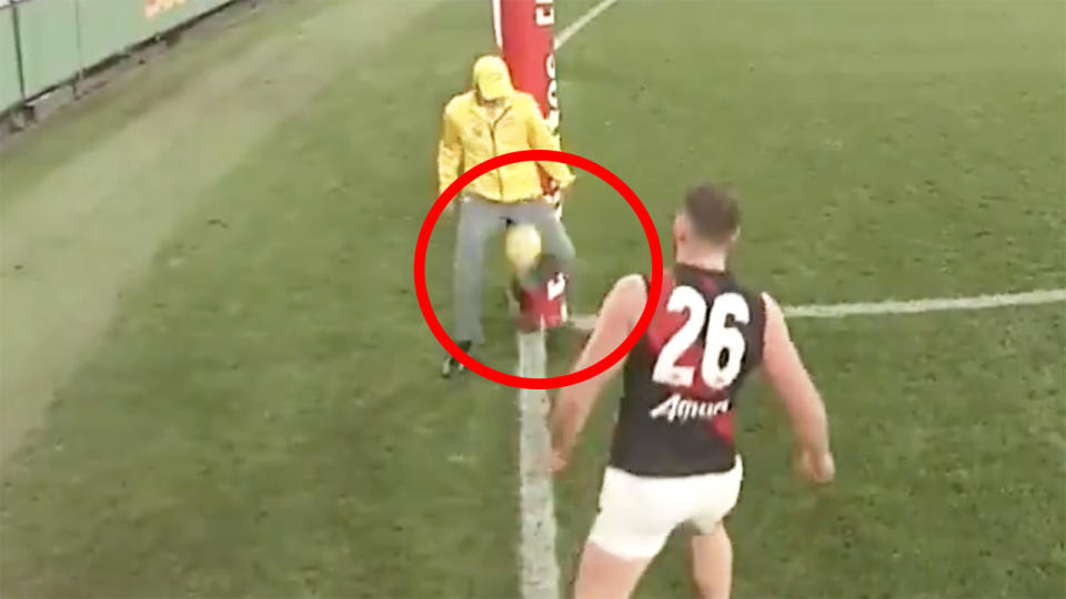 A screenshot shows the goal umpire in Friday night's Collingwood vs Essendon AFL match being struck by the ball, after Jordan de Goey's shot on goal.