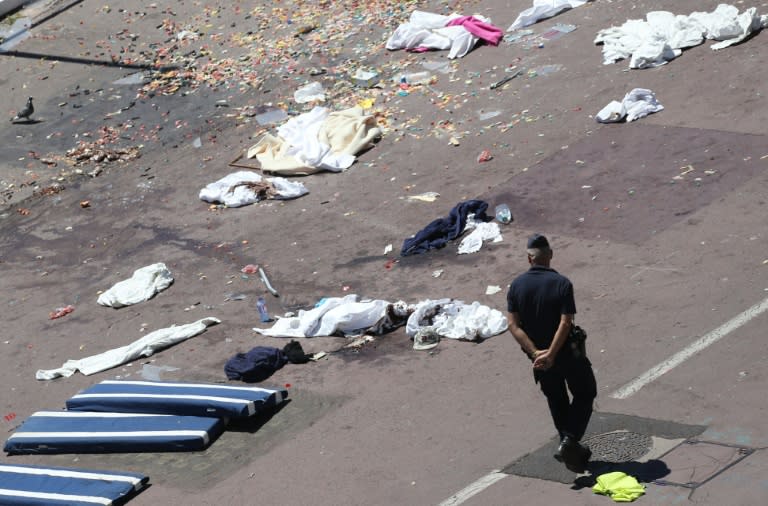 French police walk past clothes and mattresses at the site of the deadly attack on the Promenade des Anglais seafront in Nice, on July 15, 2016