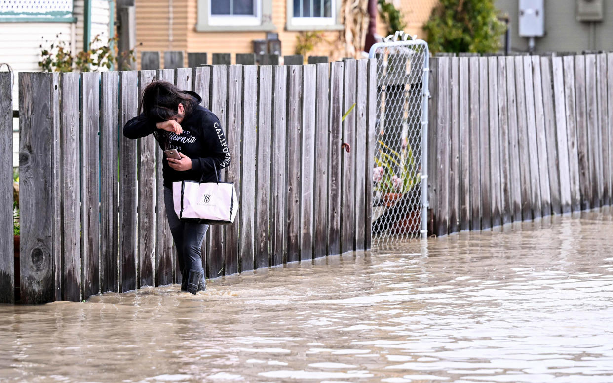 A resident treads through flood waters to reach her home in Pajaro, Calif., on March 11, 2023. (Josh Edelson / AFP - Getty Images file)