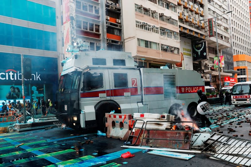 A water cannon vehicle is seen driving through a burning barrier during march in Hong Kong