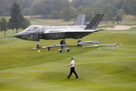 A member of the Royal Navy walks past a model of a F-35 on the fairway at Celtic Manor golf club near Newport in Wales September 3, 2014. REUTERS/Andrew Winning