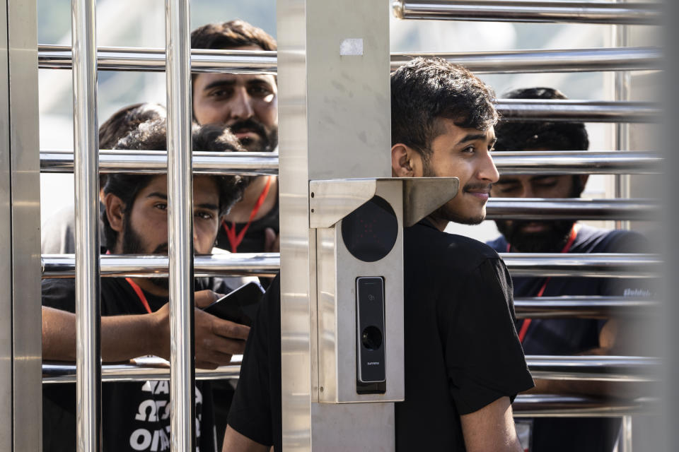 A man waits at the turnstiles and speaks with survivors of a deadly migrant boat sinking at a migrant camp in Malakasa north of Athens, on Monday, June 19, 2023. Hundreds of migrants are believed to be missing after a fishing trawler sank off southern Greece last week. (AP Photo/Petros Giannakouris)