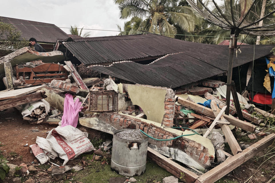 A man inspects a damaged house following an earthquake in Talamau, West Sumatra, Indonesia, Friday, Feb. 25, 2022. The strong and shallow earthquake hit off the coast of Indonesia's Sumatra island on Friday, panicking people in Sumatra island and neighboring Malaysia and Singapore. (AP Photo/Suryo Wibowo)