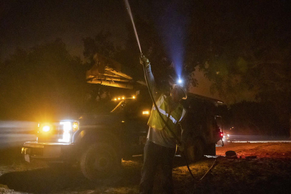 FILE - In this Sept. 28, 2020 file photo, a Pacific Gas and Electric employee sprays water on a burning telephone pole at the Zogg Fire near Ono, Calif. California's largest utility company said its equipment might have caused a fatal wildfire last month in a county in the northern part of the state, the Mercury News reported Saturday, Oct. 10, 2020. (AP Photo/Ethan Swope, File)