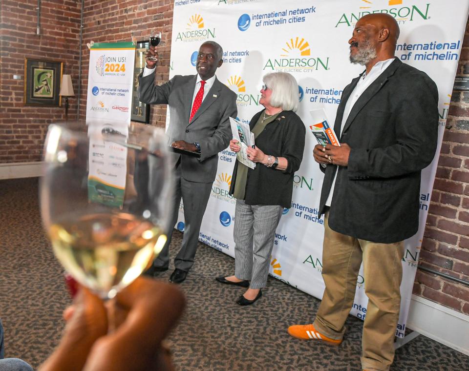 Mayor Terence Roberts, left, offers a toast with the crowd after announcing Diann Simms, middle right, and fellow artist Herman Keith, Jr. of Anderson, in connection with the City of Clermont-Farrand, France with City of Anderson, at the Anderson Arts Center Tuesday, October 10, 2023. Artist Diann Simms, and Herman Keith, Jr. of Anderson were selected to visit France. Simms to attend the Travel Diary Artist Festival in November, and Keith an artist in residency in the France city in February and March 2024. In February 2023, the City of Anderson was selected to host the fourth Conference of the International Network of Michelin Cities, to be held in April 2024 with a "Drivers of Economic Development" theme.