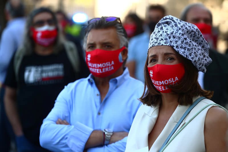 A demonstrator wears a chef cap and a protective face mask reading "save the hostelry sector" during a protest in Madrid