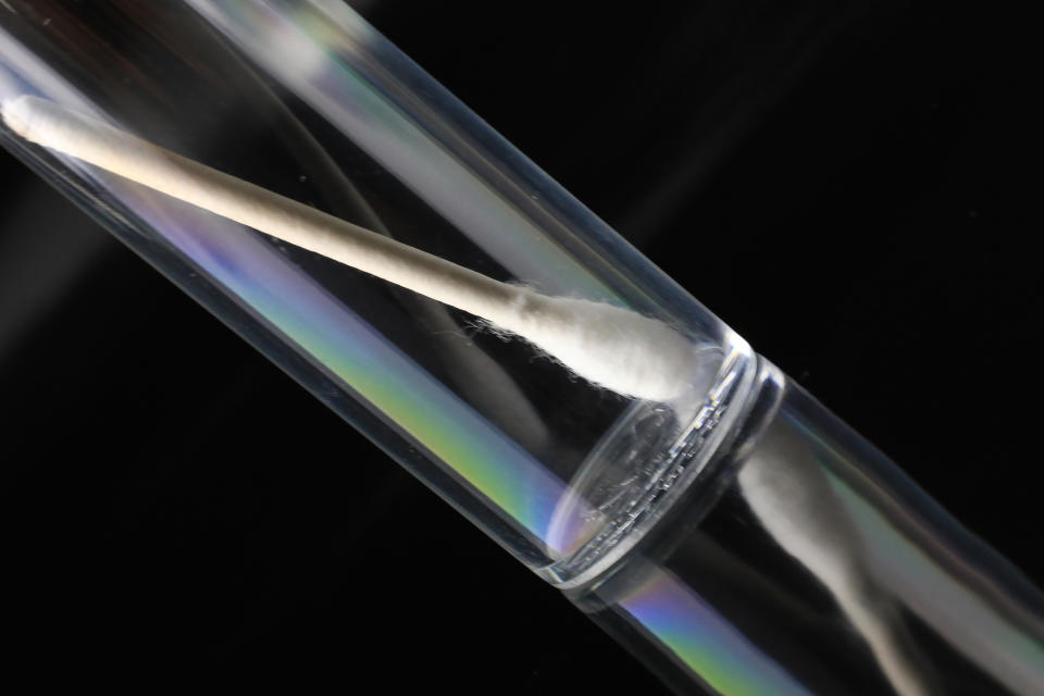 A cotton swab inside a test tube indicating a medical exam or sample collection, relevant to parental concerns about health