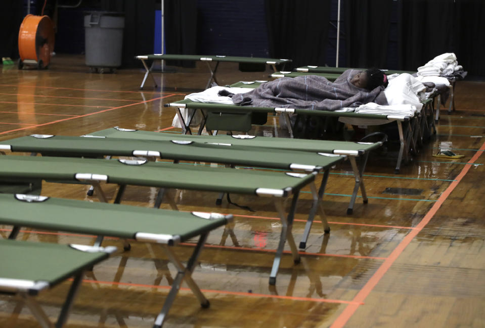 In this June 13, 2019 photo, a migrant woman sleeps on a cot inside the Portland Exposition Building in Portland, Maine. Maine's largest city has repurposed the basketball arena as an emergency shelter in anticipation of hundreds of asylum seekers who are headed to the state from the U.S. southern border. Most are arriving from Congo and Angola. (AP Photo/Elise Amendola)