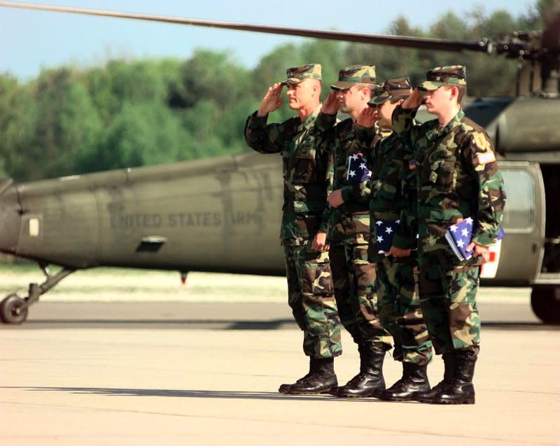 Staff Sgt. Chris Stone (L), Staff Sgt. Andrew Ramirez (C) and Specialist Steven Gonzales, the three soldiers from the 1st Infantry Division who were captured by Yugoslavian forces, salute the colors after returning to Germany with the Rev. Jesse Jackson who was instrumental in their release. File Photo by Ken Bergmann/USAF