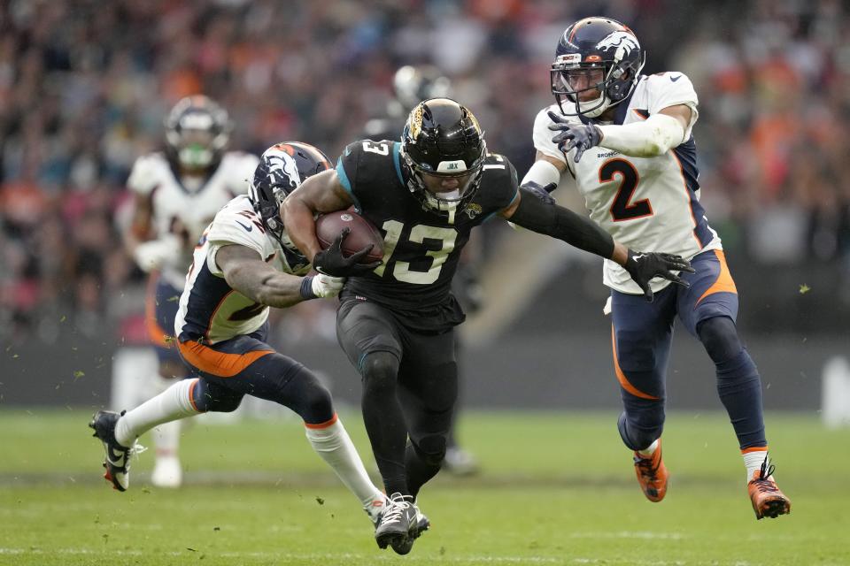 Jacksonville Jaguars wide receiver Christian Kirk (13), centre, is tackled by Denver Broncos safety Kareem Jackson (22), left, and Denver Broncos cornerback Pat Surtain II (2) during the NFL football game between Denver Broncos and Jacksonville Jaguars at Wembley Stadium London, Sunday, Oct. 30, 2022. (AP Photo/Kirsty Wigglesworth)