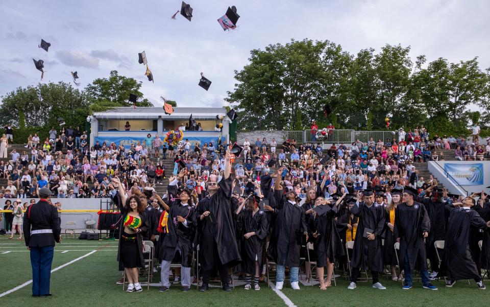 The mortarboards go flying during the Rogers High graduation ceremony for the Class of 2022 at Toppa Field on Friday.