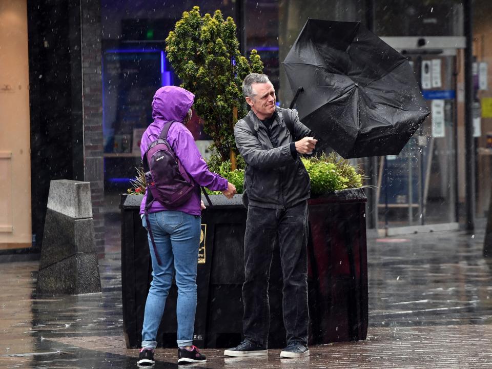 A couple battles with the elements in Glasgow city centre (AFP via Getty Images)