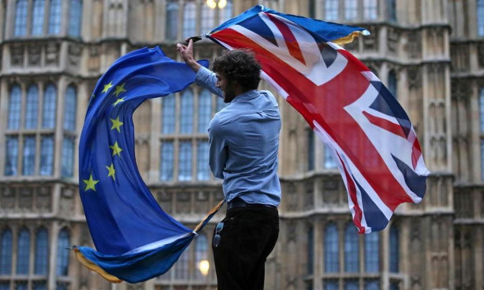 A man waving both a union jack and a European flag outside parliament in London.