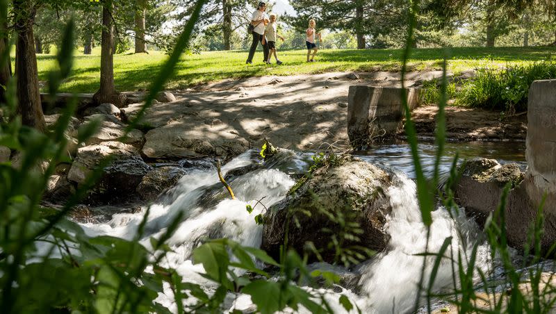 A family keeps a safe distance from rushing water where Parleys Creek flows into the pond at Sugar House Park in Salt Lake City on Thursday, June 1, 2023. Officials are warning people and their pets to stay clear of rivers and creeks swollen by spring snowmelt.