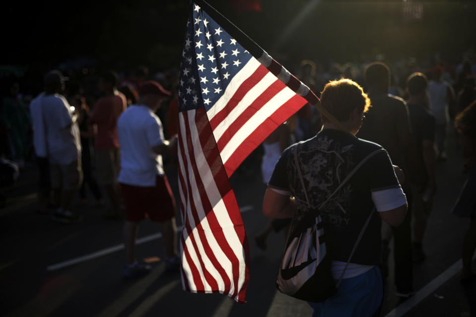 FILE - A young man walks with an American flag at an Independence Day celebration on the Benjamin Franklin Parkway, July 4, 2013, in Philadelphia. Flags proliferate every July Fourth, but unlike the right to assemble or trial by jury, their role was not prescribed by the founders: They would have been rare during early Independence Day celebrations. (AP Photo/Matt Rourke, File)