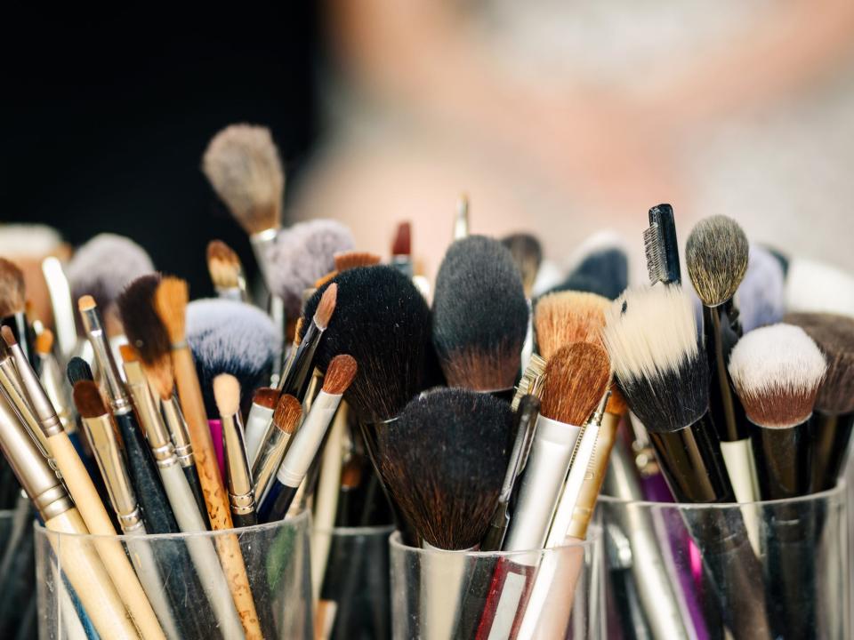 Different-sized makeup brushes in clear-acrylic cups.