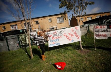 A resident puts up a banner as community members gather in a park to discuss gang violence in Manenberg township, Cape Town