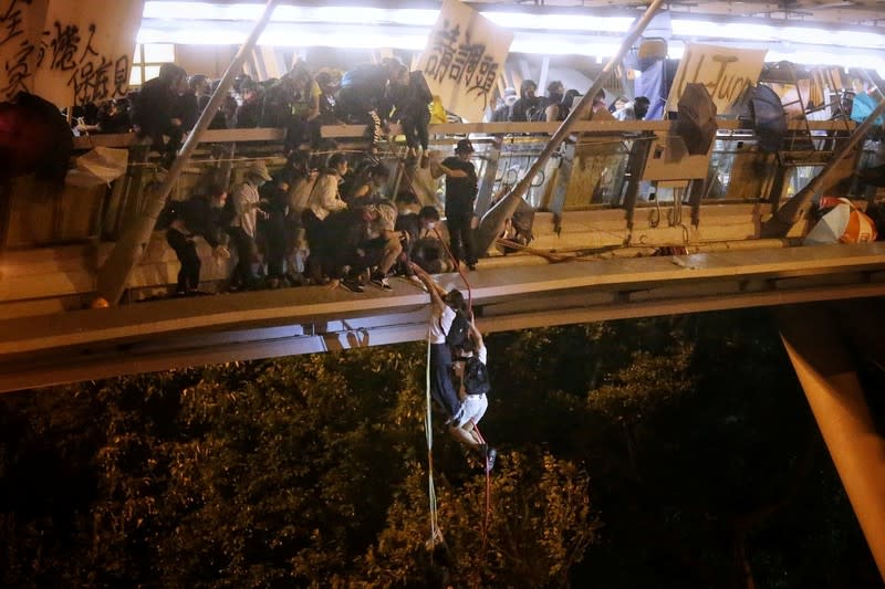 Anti-goverment protesters trapped inside Hong Kong Polytechnic University abseil onto a highway and escape before being forced to surrender during a police besiege of the campus in Hong Kong