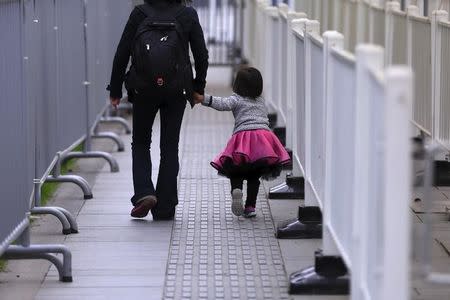 A little girl walks with her mother between barriers outside a subway station in Shanghai, China, October 30, 2015. REUTERS/Aly Song/Files